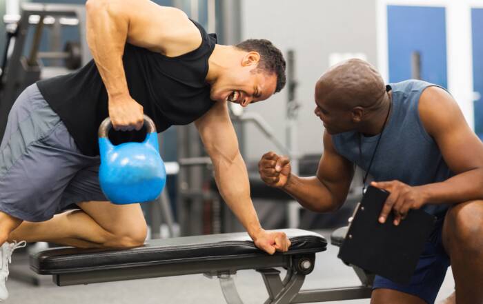 exercise science personal trainer coaching a man through a kettleball exercise