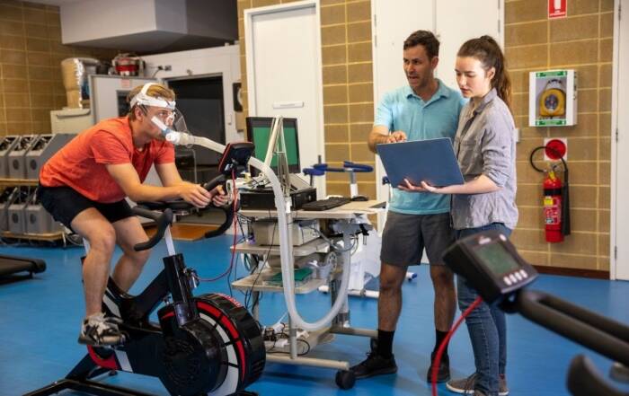 Trainers using scientific equipment to assess athlete performance during a certification-based fitness session