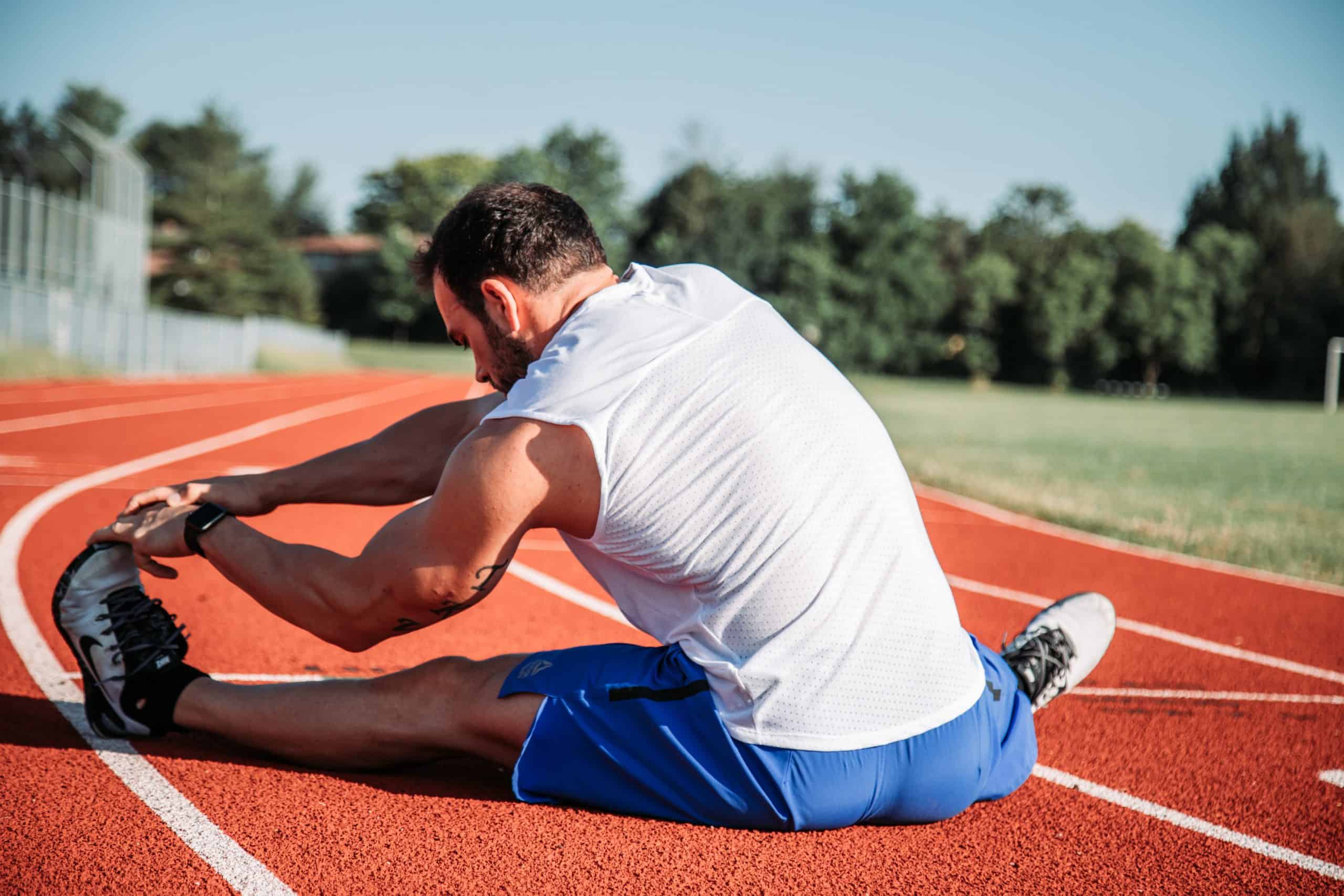 man stretching legs in a race track