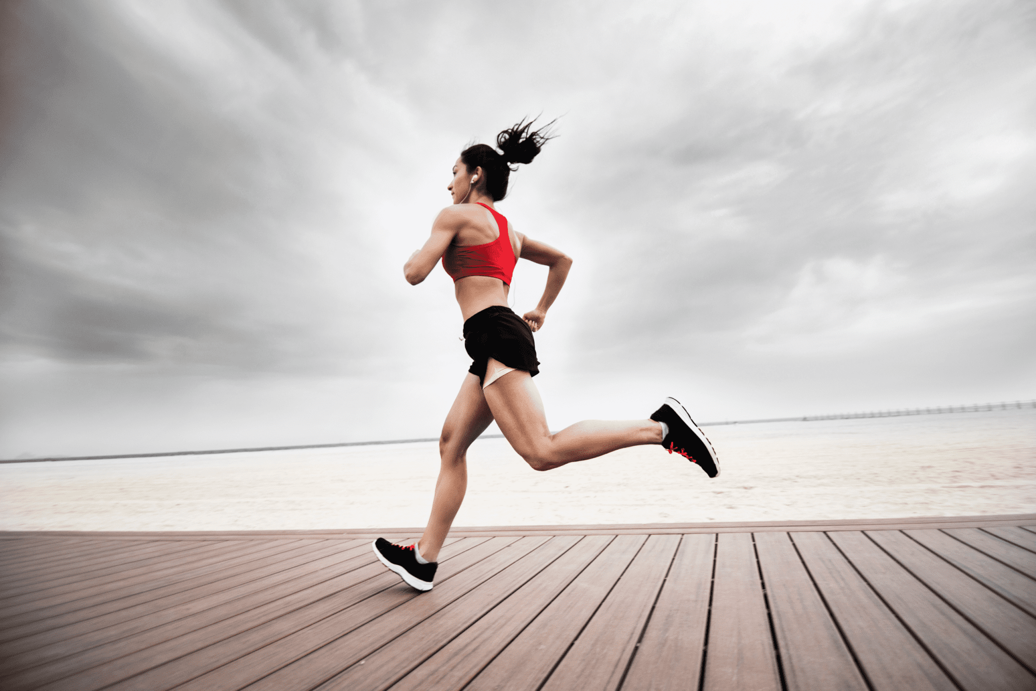 female running on boardwalk alongside ocean