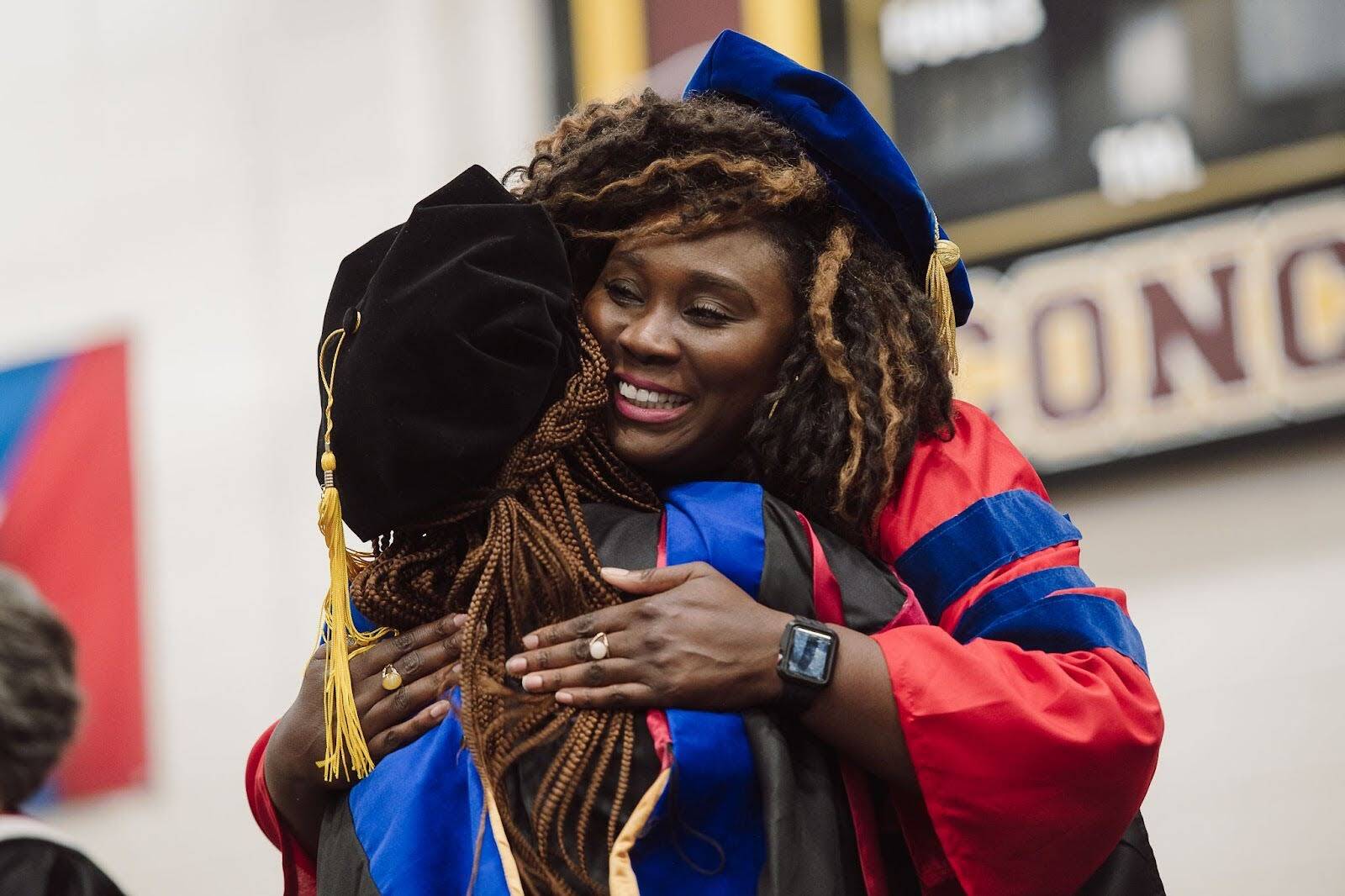 Two graduates in academic regalia embracing at a graduation ceremony, celebrating educational achievement and career growth.