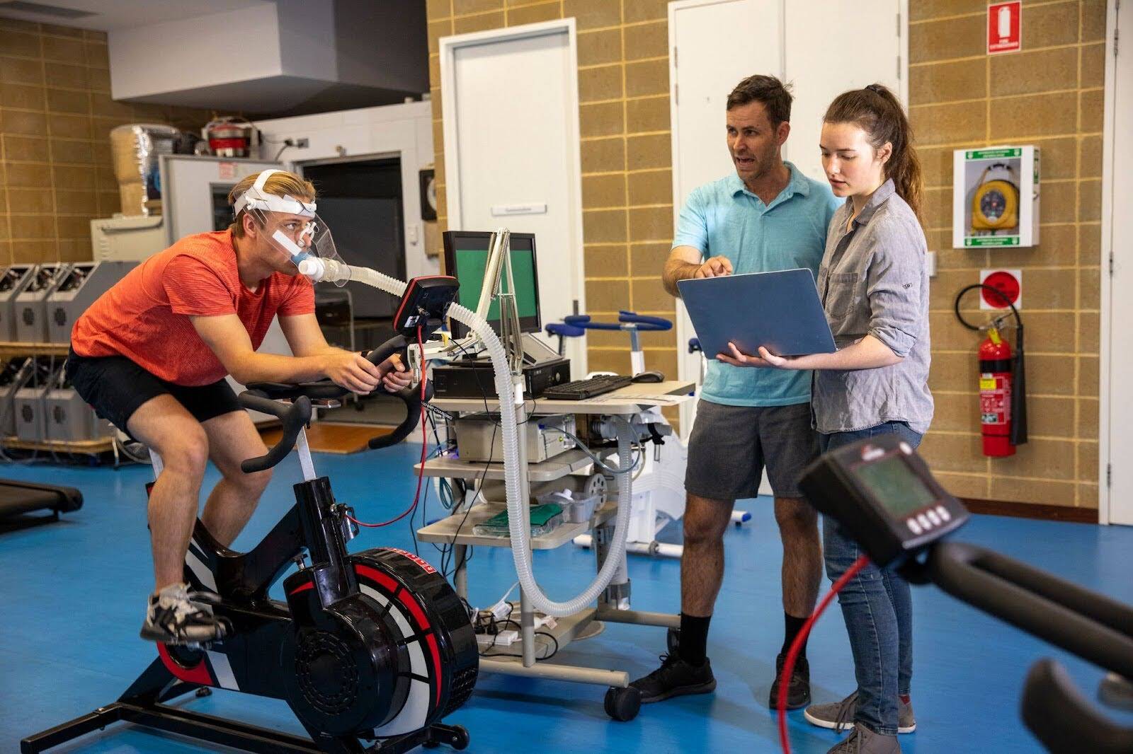 Trainers using scientific equipment to assess athlete performance during a certification-based fitness session