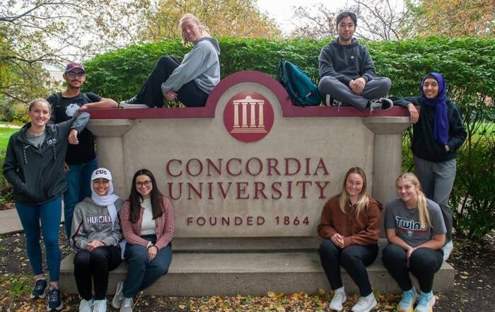 Students gathered at Concordia University sign, symbolizing campus community and college choice.