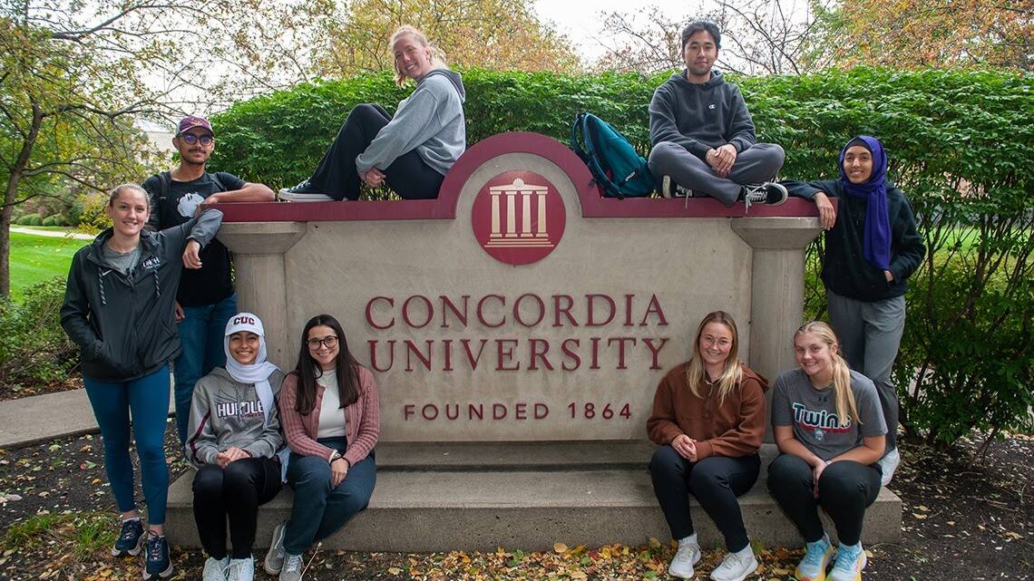 Students gathered at Concordia University sign, symbolizing campus community and college choice.