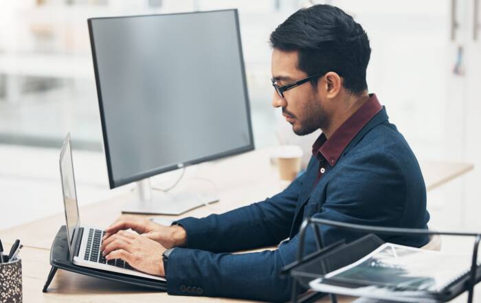 Adult student researching online college options on a computer in a modern workspace