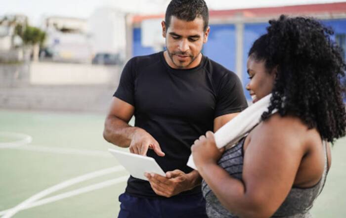 Coach discussing training plan with athlete on a sports court using a digital tablet